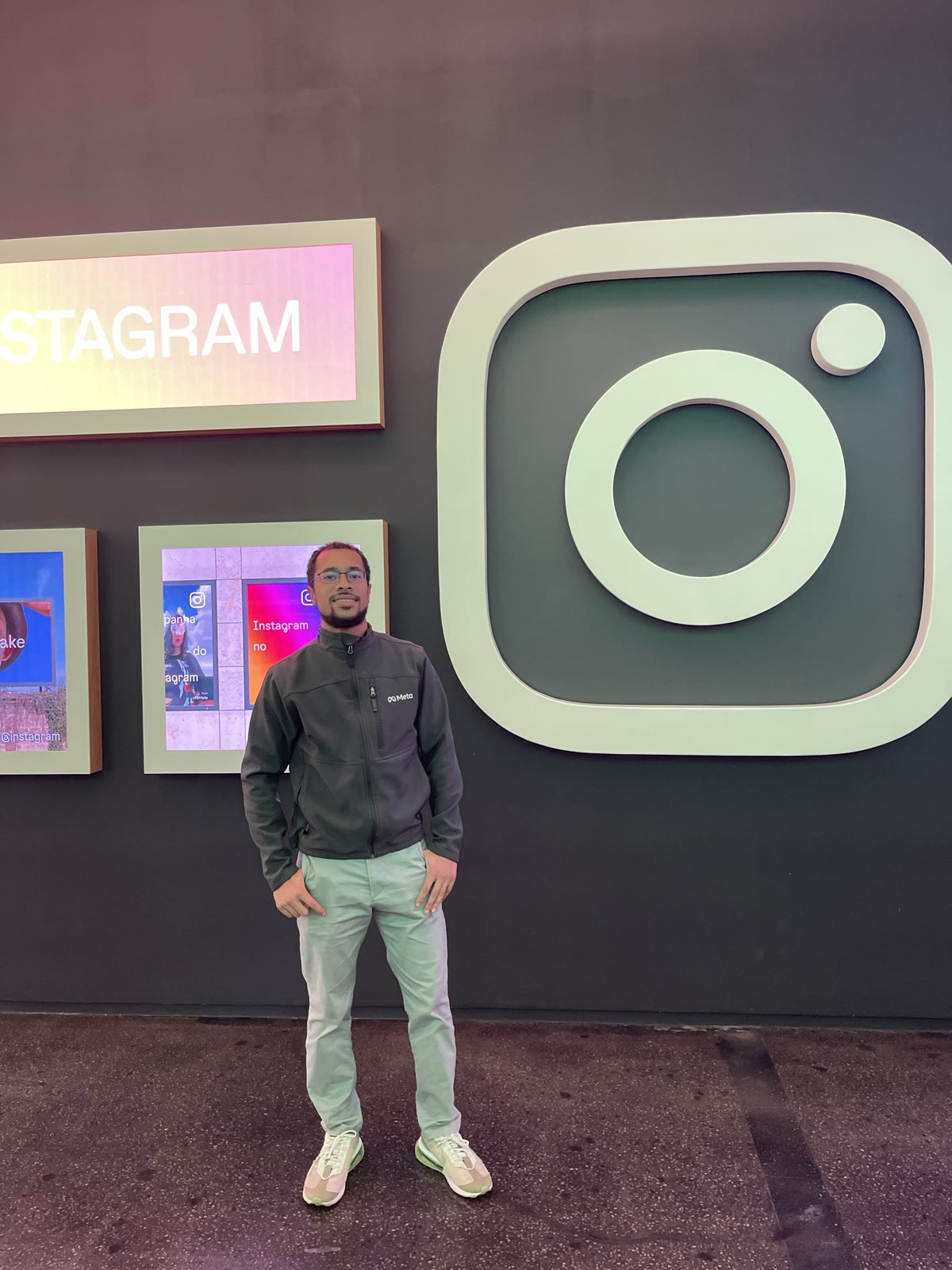 Ben Harvey standing in front of the large Instagram logo on the wall at Meta